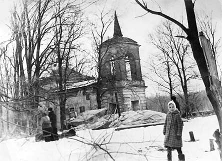 Архивное фото: за девочкой видна землянка монахов, накрытая полиэтиленом и с печной трубой, которую поддерживают три ветки