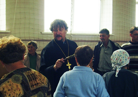 Священник беседует с пострадавшими жителями поселка Урман