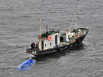 A tugboat hauls the wrecked vessel of the Solovki monk and laborer.