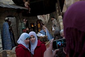 Two Palestinian Muslim women pose for a snapshot in front a nativity scene inside the Church of Nativity, Bethlehem, Saturday, Dec. 24, 2011. (Bernat Armangue / AP)