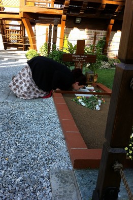 A woman praying at the Elder's grave in Souroti. Photo: Gordon Fairclough/The Wall Street Journal.