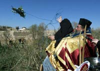 Архимандрит Иерусалимской Православной Церкви бросает крест в реку Иордан с иорданского берега. Фото Reuters/Ali Jarekji