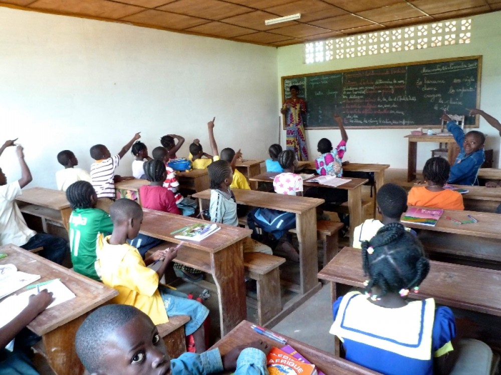 Урок в школе. За партами сидят по двое. Урок в школе «Свет народов», Долизи. За партами сидят по двое, а не как в большинстве школ (по трое); во многих государственных школах в начальных классах часто нет даже парт, малыши сидят на полу.