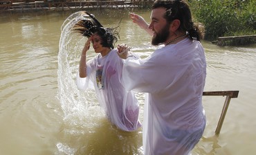 A christian pilgrim emerges from the water during a baptism ceremony in the Jordan River.