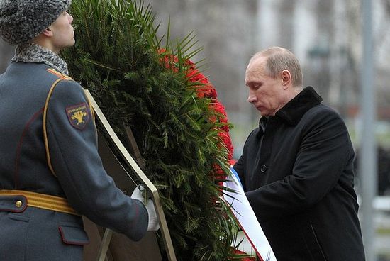 Владимир Путин поправляет ленточку с надписью ленточку в цветах российского флага и надписью: 