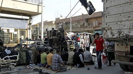 Сирийцы молятся в Ракке на фоне джихадистских флагов