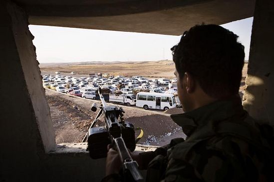 Солдат иракских сил безопасности смотрит на машины беженцев, скопившиеся на границе с иракским Курдистаном в Ибриле. REUTERS/Jacob Russell