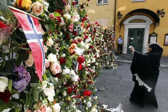 Мусульманка фотографирует цветы у кафедрального собора Осло. 2011. Reuters 