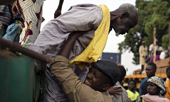 Father Bernard Kenvi helps a Muslim man climb down from an open truck in Bossemptele, Central African Republic. Photograph: Siegfried Modola/Reuters