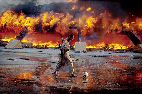 Мятежник играет в футбол на фоне пылающей резиденции М.Каддафи. Фото: Philippe de Poulpiquet, Archive/MAXPPP/ZUMA