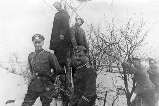 Немецкие солдаты фотографируются на фоне двоих повешенных советских партизан
