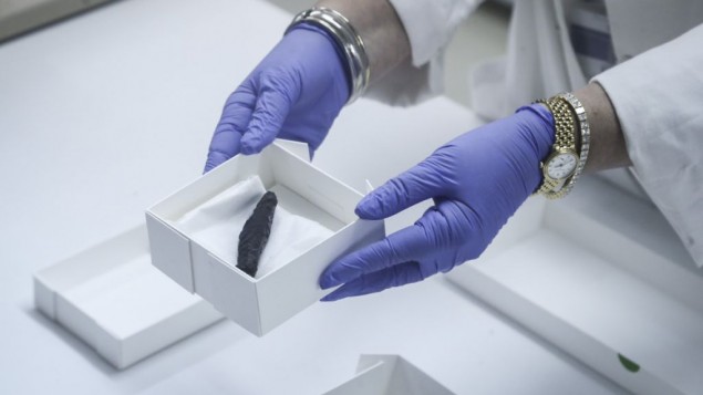 A scrap of a torched Torah scroll being shown by staff in a lab of the Israel Antiquities Authority on July 20, 2015. 