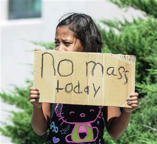 Aaliyah Doninguez, 11, holds a sign advising parishioners in Las Cruces, New Mexico, that Mass at Holy Cross Catholic Church mass was canceled on Sunday. Robin Zielinski / AP