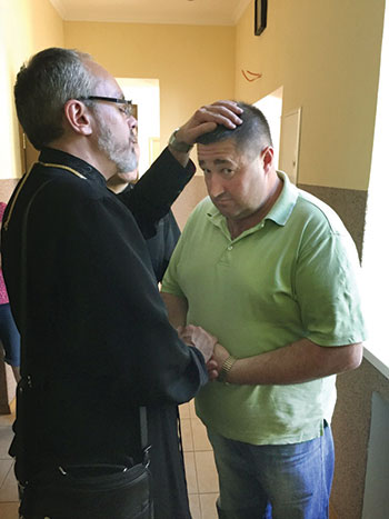 Bishop Daniel prays for a refugee resident of the LOGOS Center in Kyiv.