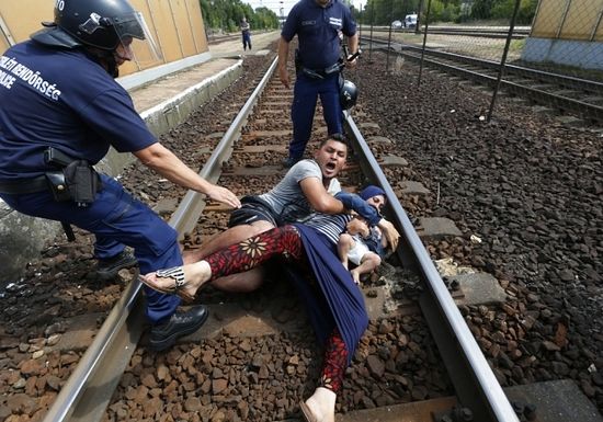 Hungarian policemen stand by the family of migrants as they wanted to run away at the railway station in the town of Bicske, Hungary, September 3, 2015. A camp for refugees and asylum seekers is located in Bicske