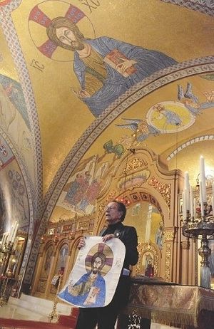 Robert Andrews holds up a drawing of the mosaic icon that is directly above him in the Transfiguration Church in Lowell Sunday. Andrews, known as "America's only true Byzantine mosaic iconographer," completed all the icons at the Greek orthodox church in Lowell. SUN photos / Caley McGuane 