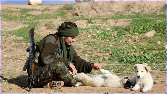Assyrian Christian Lucia, member of the battalion called the "Female Protection Forces of the Land Between the Two Rivers" fighting the Islamic State group, plays with a dog during a training on December 1, 2015 at their camp in the town of al-Qahtaniyah, near the Syrian-Turkish border (aka Kabre Hyore in Syriac, and Tirbespi in Kurdish) (AFP/DELIL SOULEIMAN).