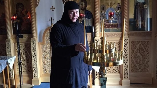 Mother Magdalene in chapel at convent lighting beeswax tapers that they make at the convent - candle is the only source of light in the chapel as there is no electricity. (Maureen Brosnahan/CBC)