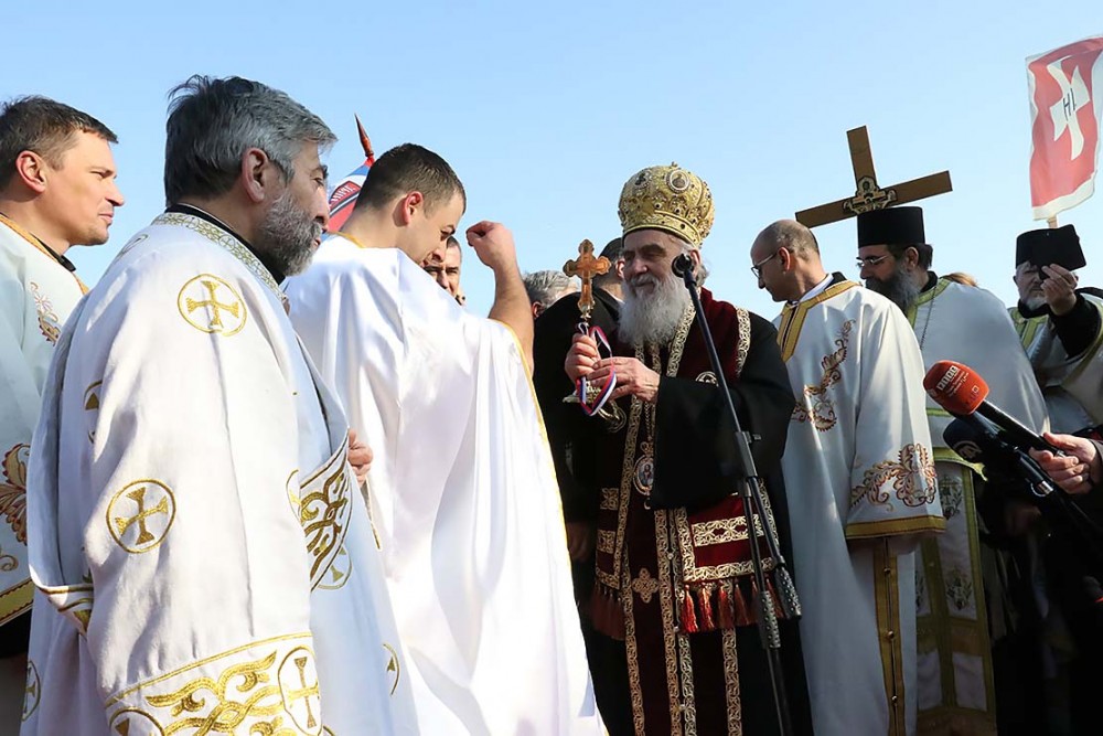 Patriarch Irenej awards the winner of the swim with a cross. 