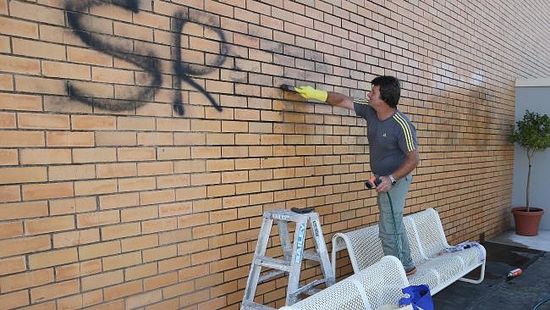 President of the Serbian Community and church, Miroslav Perisic cleans the graffiti from the church walls. Picture: Mike Dugdale