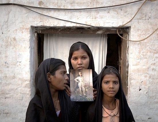 The daughters of Asia Bibi with an image of their mother, standing outside their residence in Sheikhupura on November 13, 2010.