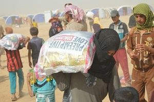 Families at a camp outside Fallujah receive aid during a sandstorm.