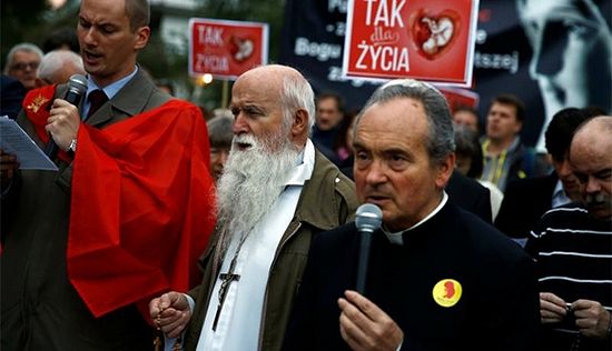 A clergyman and others pray as they take part in Sept. 22 pro-life rally in front of the parliament in Warsaw, Poland. Banners read: "Yes for life." (CNS photyo/Kacper Pempel, Reuters)