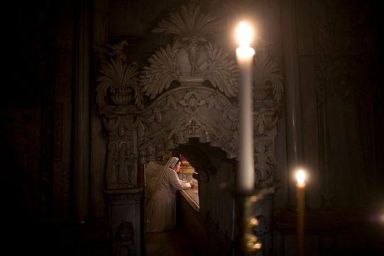 A Christian nun kneels in prayer at the "burial bed" of Christ inside the tomb shrine, known as the Edicule. PHOTOGRAPH BY ODED BALILTY, AP FOR NATIONAL GEOGRAPHIC