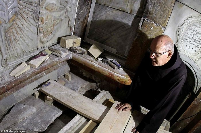 A Franciscan friar peers into the exposed tomb during the conservation work done by a team of Greek team of preservation experts in Jerusalem
