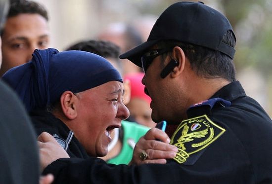A relative of one of the Cairo blast victims screams at a police officer in front of the cathedral / REUTERS