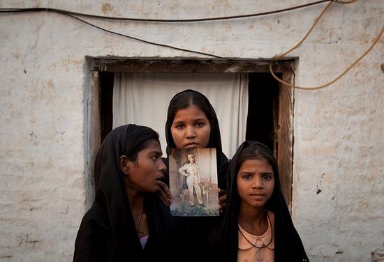 The daughters of Asia Bibi posed with an image of their mother outside their residence in Sheikhupura, located in Pakistan’s Punjab Province. (PHOTO: ADREES LATIF/REUTERS)