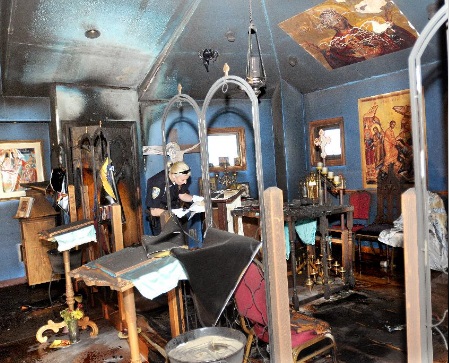 Marlboro Township police officer Alison Rosenberg looks over the damage inside St. Nikolai Orthodox Church at 9831 State St. NE Sunday morning. Photo: <a href=